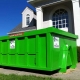 A green dumpster sitting in front of a house